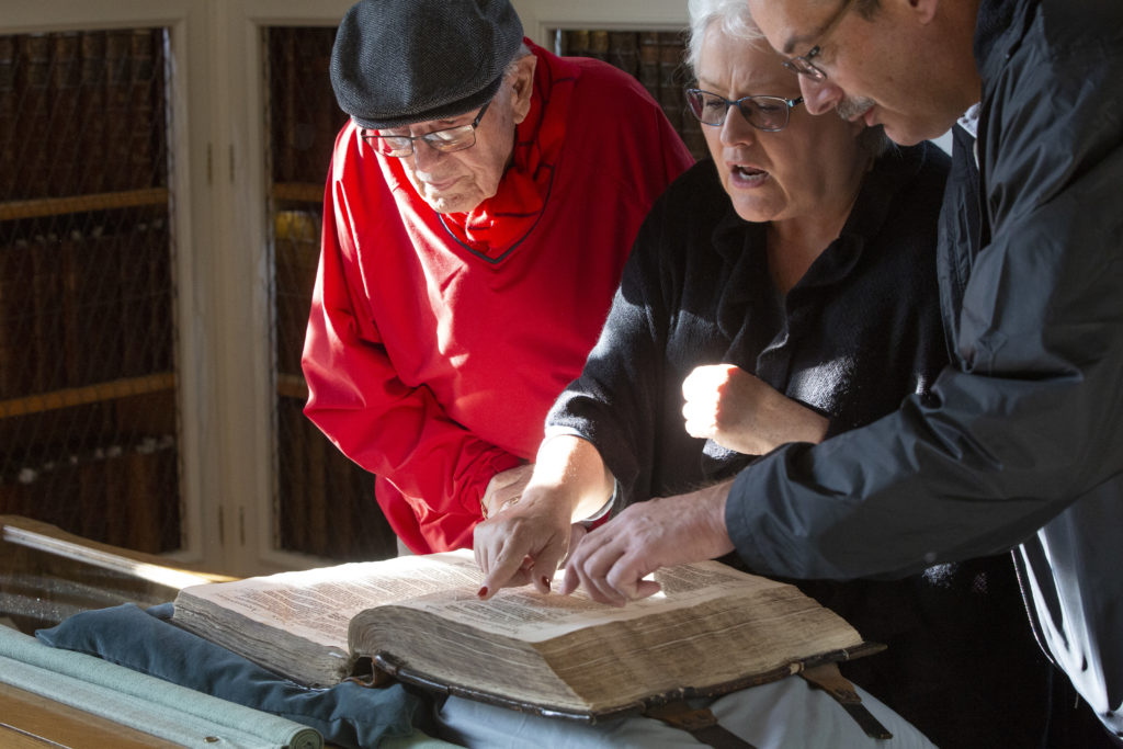 People examine an old Bible. 