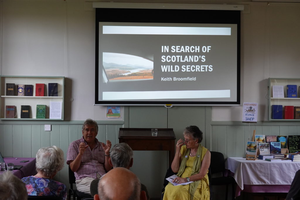 Author Keith Broomfield with Governor Steph Haxton, in front of Keith Broomfield's powerpoint presentation.